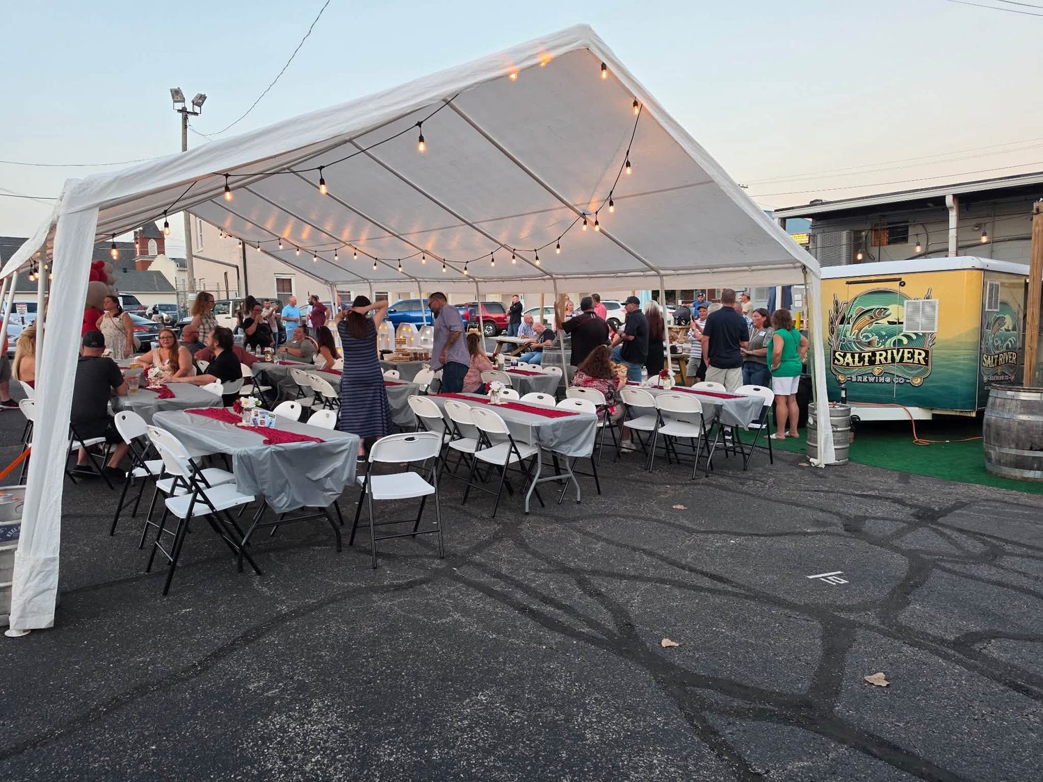 Guests at long tables under a lit tent